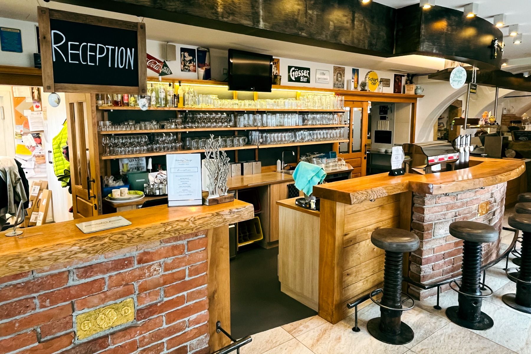 Perbersdorfer Heuriger - Hotel: Ein gemütliches, familiengeführtes Lokal in Neuhofen an der Ybbs mit Ziegel- und Holztheken, Barhockern, Bierzapfhähnen, Vintage-Dekor, mit Flaschen gefüllten Regalen und einem