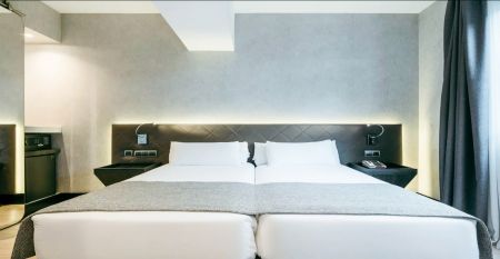 Inngangen til Hotel ILUNION Bel Art Barcelona har store glassdører, potteplanter og et skilt over den svarte markisen - perfekt for gjester som vil utforske Fußballkultur Barcelona eller besøke Trainingseinrichtungen i nærheten.