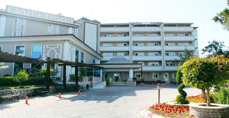 Das Linda Resort ist ein mehrst&ouml;ckiges Hotel mit Blick auf einen Au&szlig;enpool, der mit Liegest&uuml;hlen, Sonnenschirmen und Palmen unter strahlend blauem Himmel ausgestattet ist.