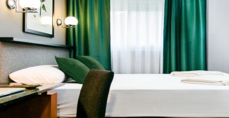 Das moderne, hellgraue Hotel Malcom & Barret Valencia*** besticht durch ein gro&szlig;es HOTEL-Schild, vor dem Motorroller und ein Auto geparkt sind &ndash; ein einladender Ort f&uuml;r die Fu&szlig;ballmannschaften aus Valencia w&auml;hrend ihres Trainingslagers.
