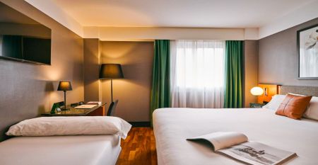 Das moderne, hellgraue Hotel Malcom & Barret Valencia*** besticht durch ein gro&szlig;es HOTEL-Schild, vor dem Motorroller und ein Auto geparkt sind &ndash; ein einladender Ort f&uuml;r die Fu&szlig;ballmannschaften aus Valencia w&auml;hrend ihres Trainingslagers.