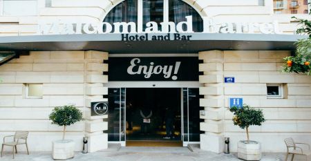 Das moderne, hellgraue Hotel Malcom & Barret Valencia*** besticht durch ein gro&szlig;es HOTEL-Schild, vor dem Motorroller und ein Auto geparkt sind &ndash; ein einladender Ort f&uuml;r die Fu&szlig;ballmannschaften aus Valencia w&auml;hrend ihres Trainingslagers.
