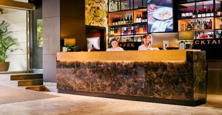 Das moderne, hellgraue Hotel Malcom & Barret Valencia*** besticht durch ein gro&szlig;es HOTEL-Schild, vor dem Motorroller und ein Auto geparkt sind &ndash; ein einladender Ort f&uuml;r die Fu&szlig;ballmannschaften aus Valencia w&auml;hrend ihres Trainingslagers.