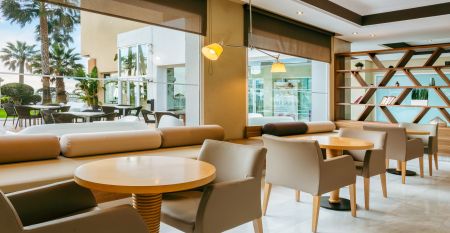 Ein hohes, gelbes Hotel Sol Guadalmar mit Balkonen blickt auf einen klaren, blauen Au&szlig;enpool, umgeben von Palmen und gr&uuml;nen Rasenfl&auml;chen unter einem sonnigen Himmel - perfekt f&uuml;r Ihren Aufenthalt in diesem zentrumsnahen 4 Sterne Hotel Malaga.