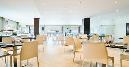 Ein hohes, gelbes Hotel Sol Guadalmar mit Balkonen blickt auf einen klaren, blauen Au&szlig;enpool, umgeben von Palmen und gr&uuml;nen Rasenfl&auml;chen unter einem sonnigen Himmel - perfekt f&uuml;r Ihren Aufenthalt in diesem zentrumsnahen 4 Sterne Hotel Malaga.
