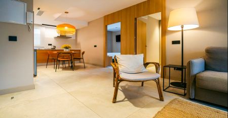 Ein Innenhof mit Palmen und Sitzgelegenheiten im Freien ist von modernen wei&szlig;en Geb&auml;uden umgeben, mit einem Hotel Zenit Sevilla-Schild - ideal f&uuml;r Fu&szlig;ball-Sportgruppen - und einem gro&szlig;en Geb&auml;ude mit der Aufschrift GOOD NIGHT auf dem Dach.