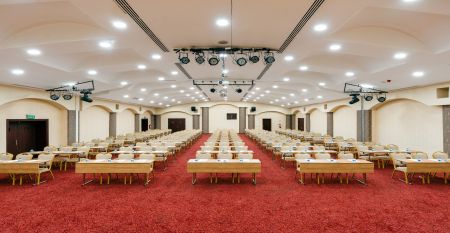 Luftaufnahme des Hotels Limak Arcadia mit Pools, Gärten, Sportplätzen und Strandkabinen - ideal für das Fußballtrainingslager Türkei - inmitten von Palmen und Bergen unter einem klaren Himmel.