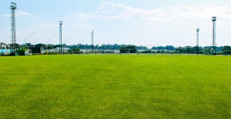 Luftaufnahme des Hotels Limak Arcadia mit Pools, Gärten, Sportplätzen und Strandkabinen - ideal für das Fußballtrainingslager Türkei - inmitten von Palmen und Bergen unter einem klaren Himmel.