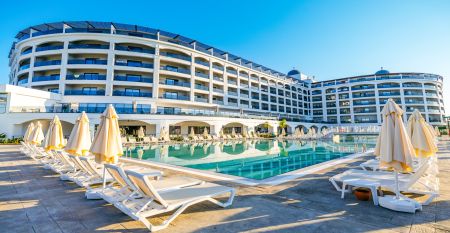Das Side Moon Palace ist ein modernes Hotel mit mehreren Etagen und Balkonen, von denen aus man den Blick auf einen gro&szlig;z&uuml;gigen Au&szlig;enpool genie&szlig;en kann, der von Reihen wei&szlig;er Liegest&uuml;hle und geschlossenen Sonnenschirmen ges&auml;umt ist.