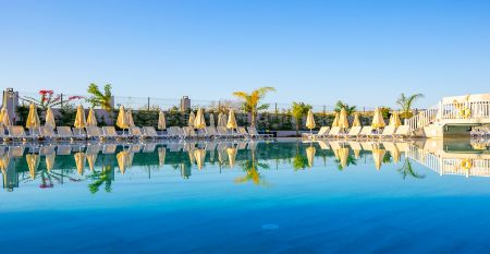 Das Side Moon Palace ist ein modernes Hotel mit mehreren Etagen und Balkonen, von denen aus man den Blick auf einen gro&szlig;z&uuml;gigen Au&szlig;enpool genie&szlig;en kann, der von Reihen wei&szlig;er Liegest&uuml;hle und geschlossenen Sonnenschirmen ges&auml;umt ist.