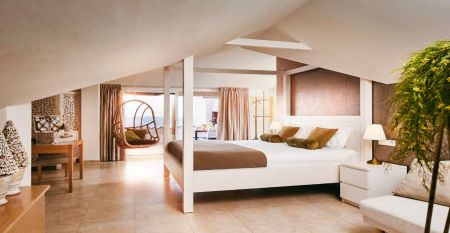 Das Van der Valk Hotel BARCAROLA ist ein 4-Sterne-Hotel im mediterranen Stil an der Costa Brava mit Balkonen mit Fahnen, einem klaren blauen Pool, Pooltischen mit Sonnenschirmen und Palmen unter einem strahlend blauen Himmel.