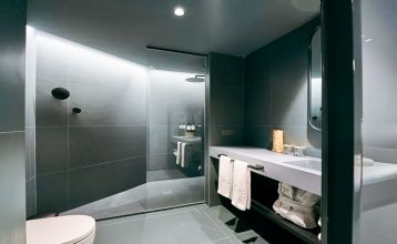Das Hotel Barcelona Princess ragt inmitten der Hochhäuser Barcelonas nahe der Küste empor, unter einem teilweise bewölkten Himmel, unter dem sich Straßen, Autos und Bäume erstrecken – ein idealer Ort für die sportliche Vorbereitung.