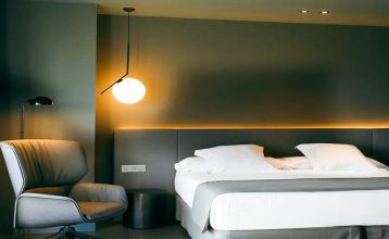 Das Hotel Barcelona Princess ragt inmitten der Hochhäuser Barcelonas nahe der Küste empor, unter einem teilweise bewölkten Himmel, unter dem sich Straßen, Autos und Bäume erstrecken – ein idealer Ort für die sportliche Vorbereitung.