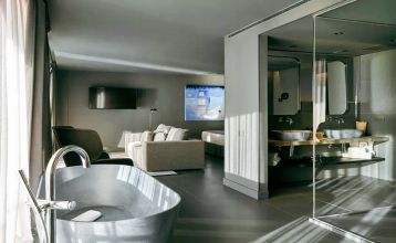 Das Hotel Barcelona Princess ragt inmitten der Hochhäuser Barcelonas nahe der Küste empor, unter einem teilweise bewölkten Himmel, unter dem sich Straßen, Autos und Bäume erstrecken – ein idealer Ort für die sportliche Vorbereitung.