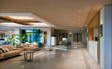Das Hotel SH Villa Gadea* ist ein Resort an der Küste mit Meerblick, einem großen weißen Gebäude, einem Pool, Palmen und grünen Rasenflächen – ideal für Fußballmannschaften während ihres Trainingslagers in Altea unter strahlend blauem Himmel.