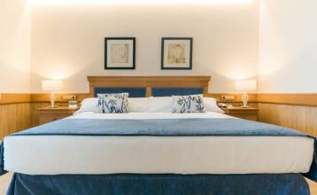 Das Hotel SH Villa Gadea* ist ein Resort an der Küste mit Meerblick, einem großen weißen Gebäude, einem Pool, Palmen und grünen Rasenflächen – ideal für Fußballmannschaften während ihres Trainingslagers in Altea unter strahlend blauem Himmel.