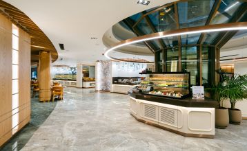 Luftaufnahme des Hotels Limak Arcadia mit Pools, Gärten, Sportplätzen und Strandkabinen - ideal für das Fußballtrainingslager Türkei - inmitten von Palmen und Bergen unter einem klaren Himmel.