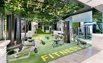 Luftaufnahme des Hotels Limak Arcadia mit Pools, Gärten, Sportplätzen und Strandkabinen - ideal für das Fußballtrainingslager Türkei - inmitten von Palmen und Bergen unter einem klaren Himmel.