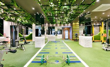 Luftaufnahme des Hotels Limak Arcadia mit Pools, Gärten, Sportplätzen und Strandkabinen - ideal für das Fußballtrainingslager Türkei - inmitten von Palmen und Bergen unter einem klaren Himmel.
