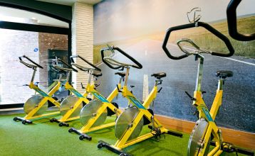 Luftaufnahme des Hotels Limak Arcadia mit Pools, Gärten, Sportplätzen und Strandkabinen - ideal für das Fußballtrainingslager Türkei - inmitten von Palmen und Bergen unter einem klaren Himmel.
