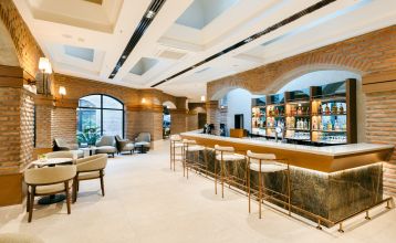 Luftaufnahme des Hotels Limak Arcadia mit Pools, Gärten, Sportplätzen und Strandkabinen - ideal für das Fußballtrainingslager Türkei - inmitten von Palmen und Bergen unter einem klaren Himmel.