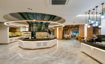 Luftaufnahme des Hotels Limak Arcadia mit Pools, Gärten, Sportplätzen und Strandkabinen - ideal für das Fußballtrainingslager Türkei - inmitten von Palmen und Bergen unter einem klaren Himmel.