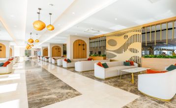 Das Side Moon Palace ist ein modernes Hotel mit mehreren Etagen und Balkonen, von denen aus man den Blick auf einen großzügigen Außenpool genießen kann, der von Reihen weißer Liegestühle und geschlossenen Sonnenschirmen gesäumt ist.
