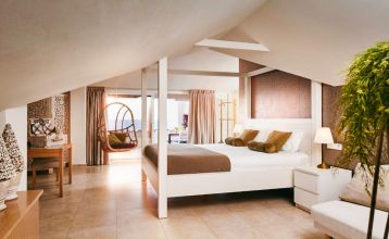 Das Van der Valk Hotel BARCAROLA ist ein 4-Sterne-Hotel im mediterranen Stil an der Costa Brava mit Balkonen mit Fahnen, einem klaren blauen Pool, Pooltischen mit Sonnenschirmen und Palmen unter einem strahlend blauen Himmel.