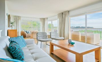 Das Van der Valk Hotel BARCAROLA ist ein 4-Sterne-Hotel im mediterranen Stil an der Costa Brava mit Balkonen mit Fahnen, einem klaren blauen Pool, Pooltischen mit Sonnenschirmen und Palmen unter einem strahlend blauen Himmel.