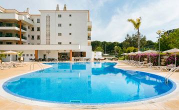 Luftaufnahme des Victoria Sports & Beach Hotels, einer modernen Anlage mit Pool, umgeben von Pinien in Albufeira, in der Nähe von Sportplätzen für Fußball-Trainingslager und unweit der sonnigen Küste.