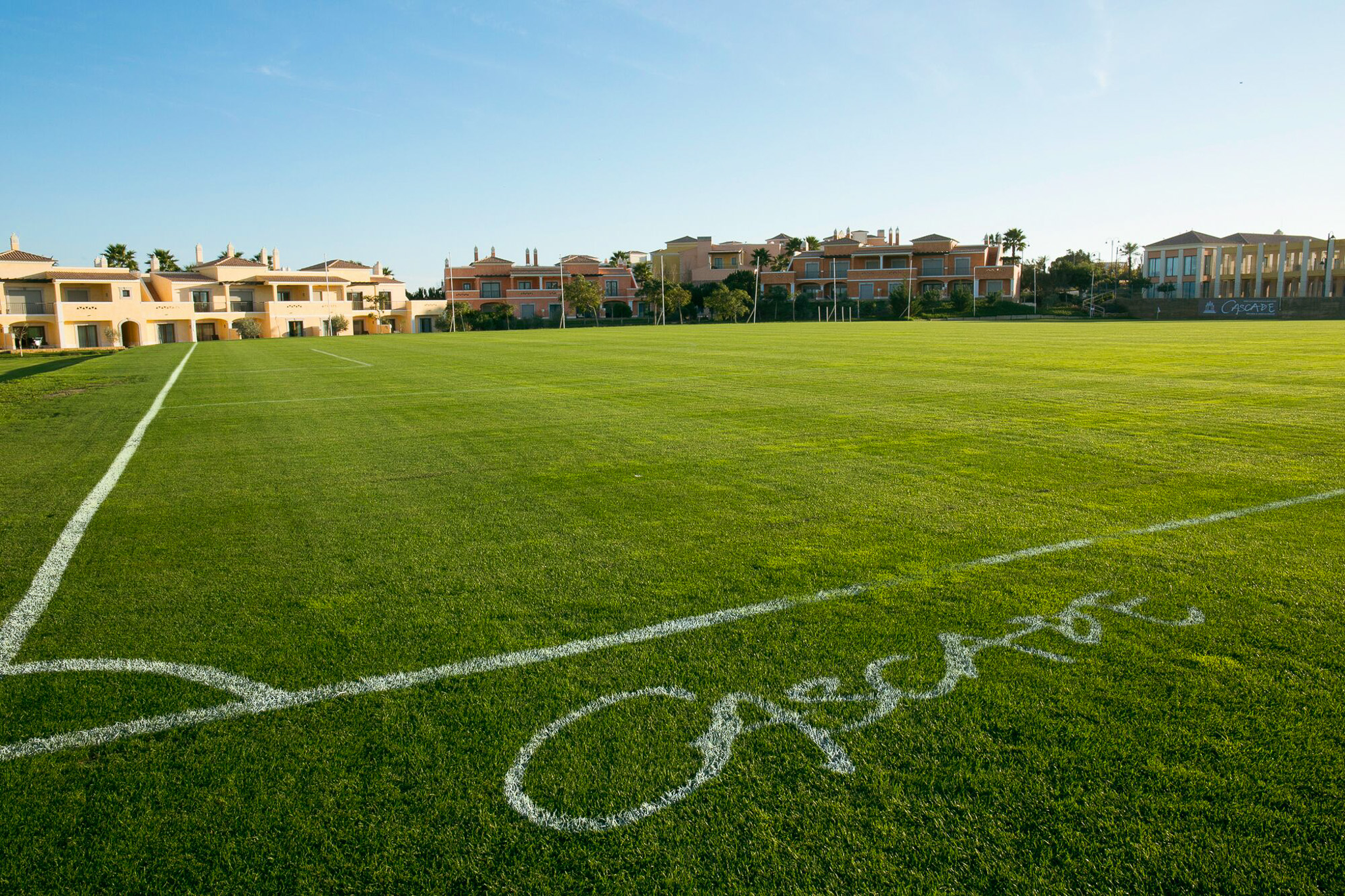 Fußballplatz in der Algarve mit direkter Hotelanbindung und Palmen im Hintergrund.