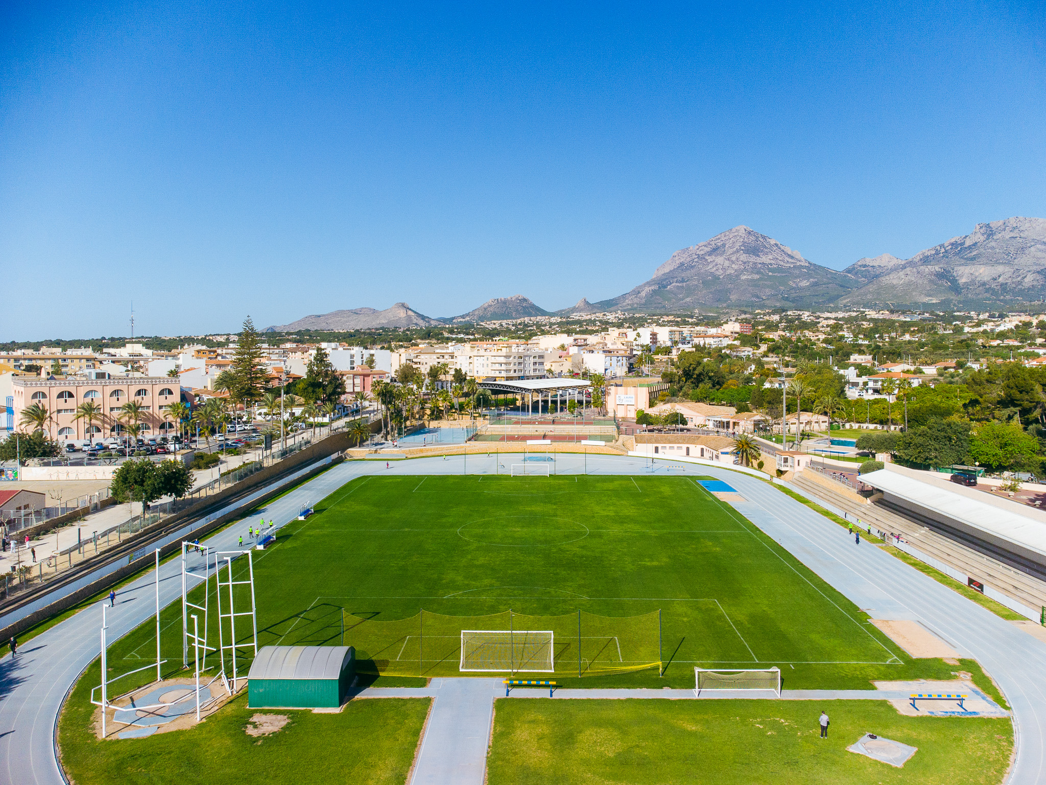 Ein gepflegtes Stadion mit Laufbahn, grüner Rasenfläche und Bergpanorama im Hintergrund.