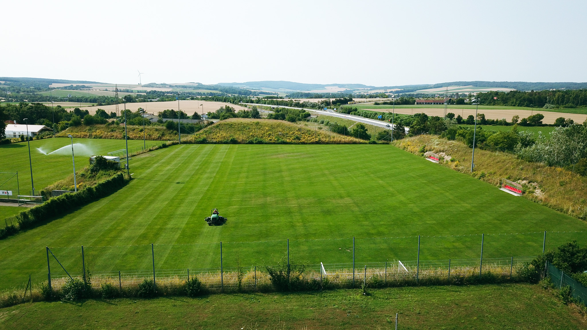 Fußballtrainingsplatz in Niederösterreich, eingebettet in eine ländliche Landschaft mit Blick auf Felder, Windräder und eine Landstraße.