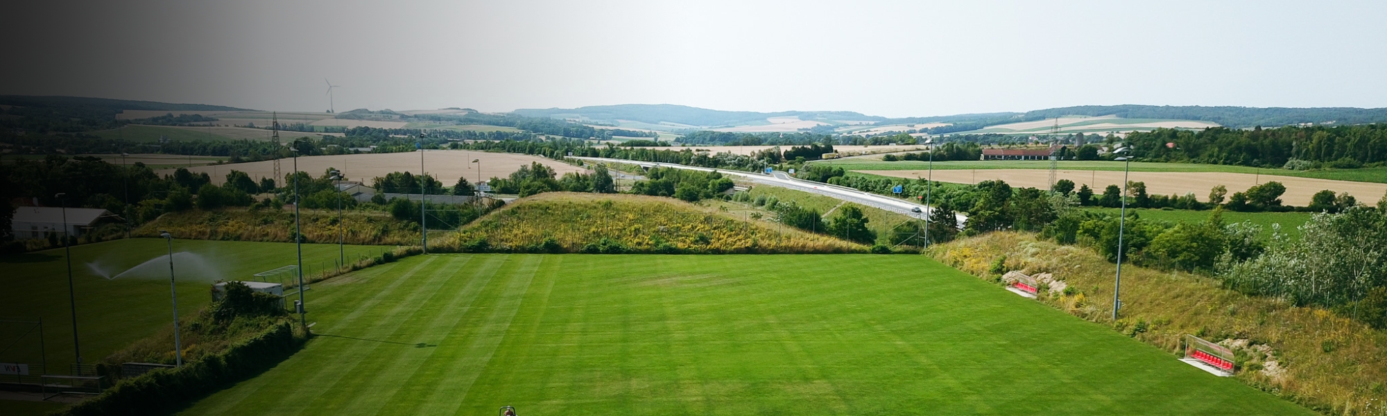 Fußballtrainingsplatz in Niederösterreich, eingebettet in eine ländliche Landschaft mit Blick auf Felder, Windräder und eine Landstraße.