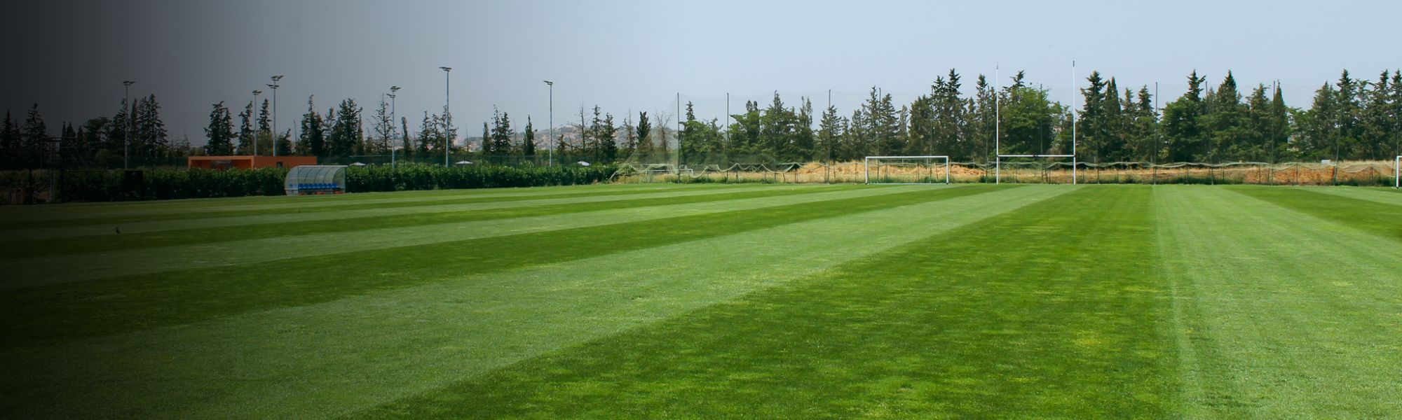Fußballplatz in Portugal, aufgenommen als Panorama mit sattem Grün und Toren im Hintergrund.