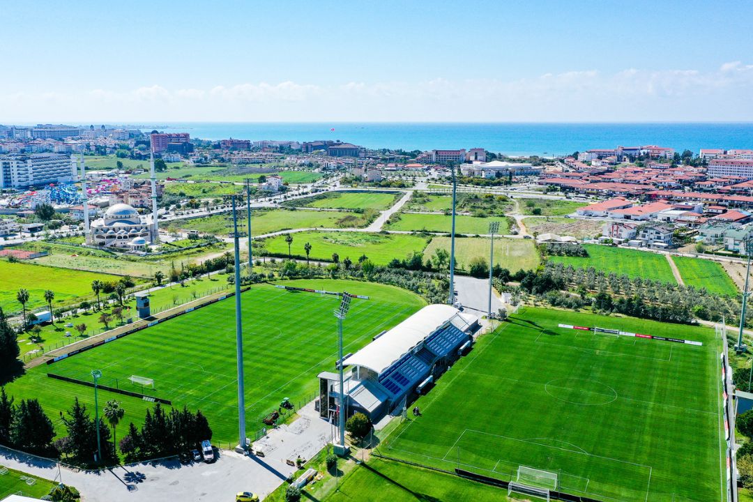 Fußballtrainingslager in der Türkei mit zwei gepflegten Fußballplätzen, umgeben von grüner Landschaft und nahe der Küste.